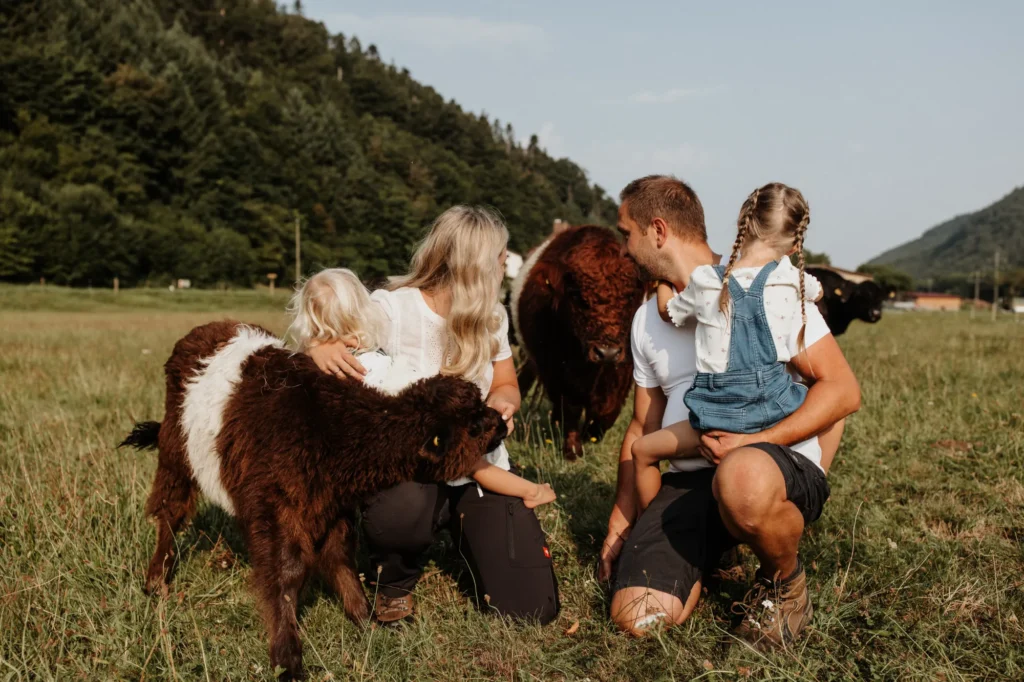Familie Schächtele steht mit zwei Kindern auf einer Wiese zwischen ihren Tieren.